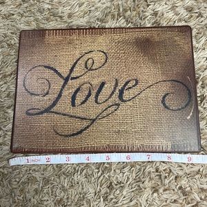 Metal wall art plaque says love with burlap background